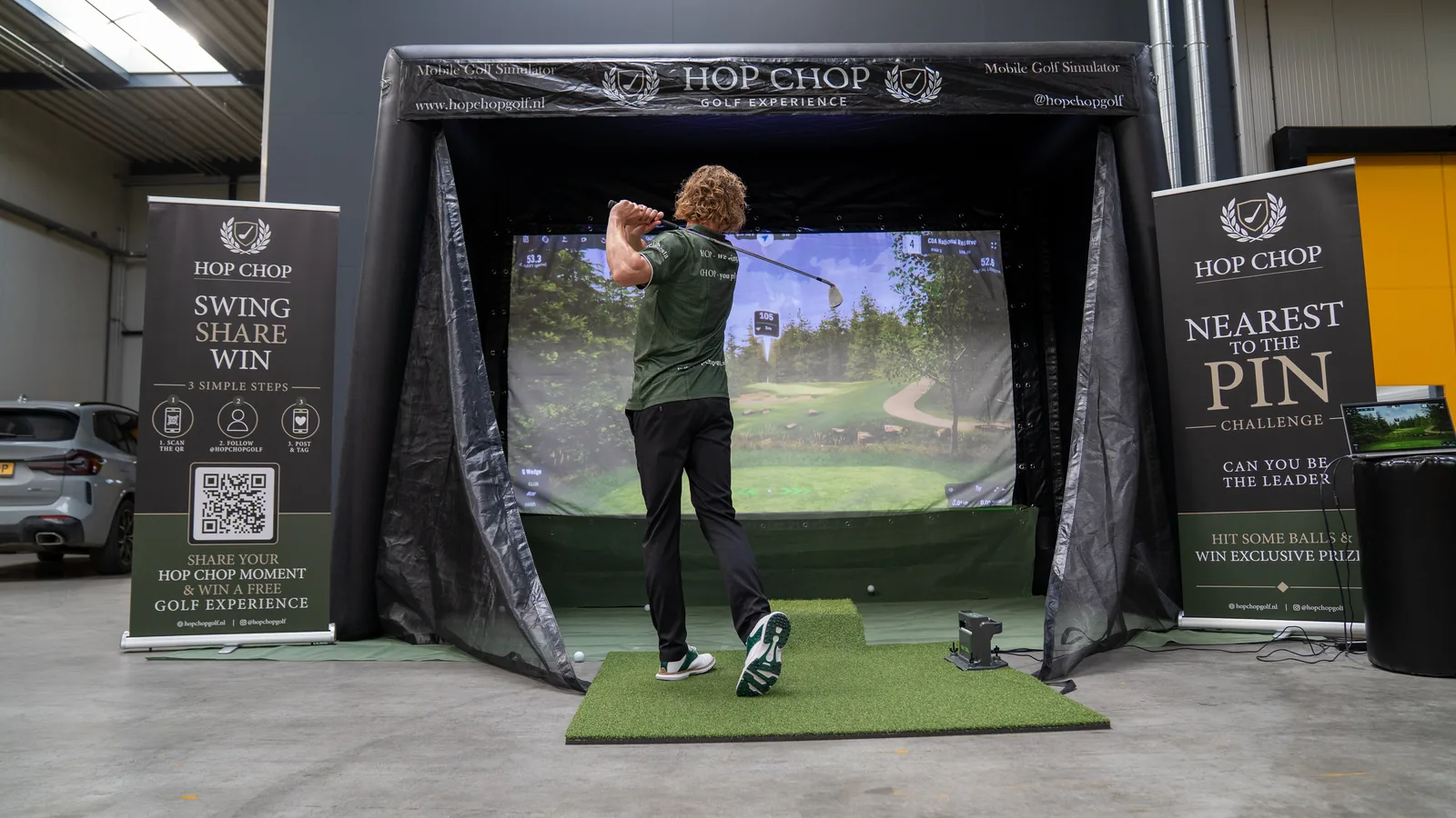 Golfer slaat af in de HOP CHOP mobiele golfsimulator naast de Nearest to the Pin Challenge banner