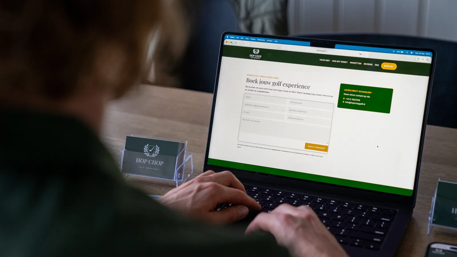 Iemand vult het aanvraagformulier van HOP CHOP in op een laptop, met visitekaartjes ernaast