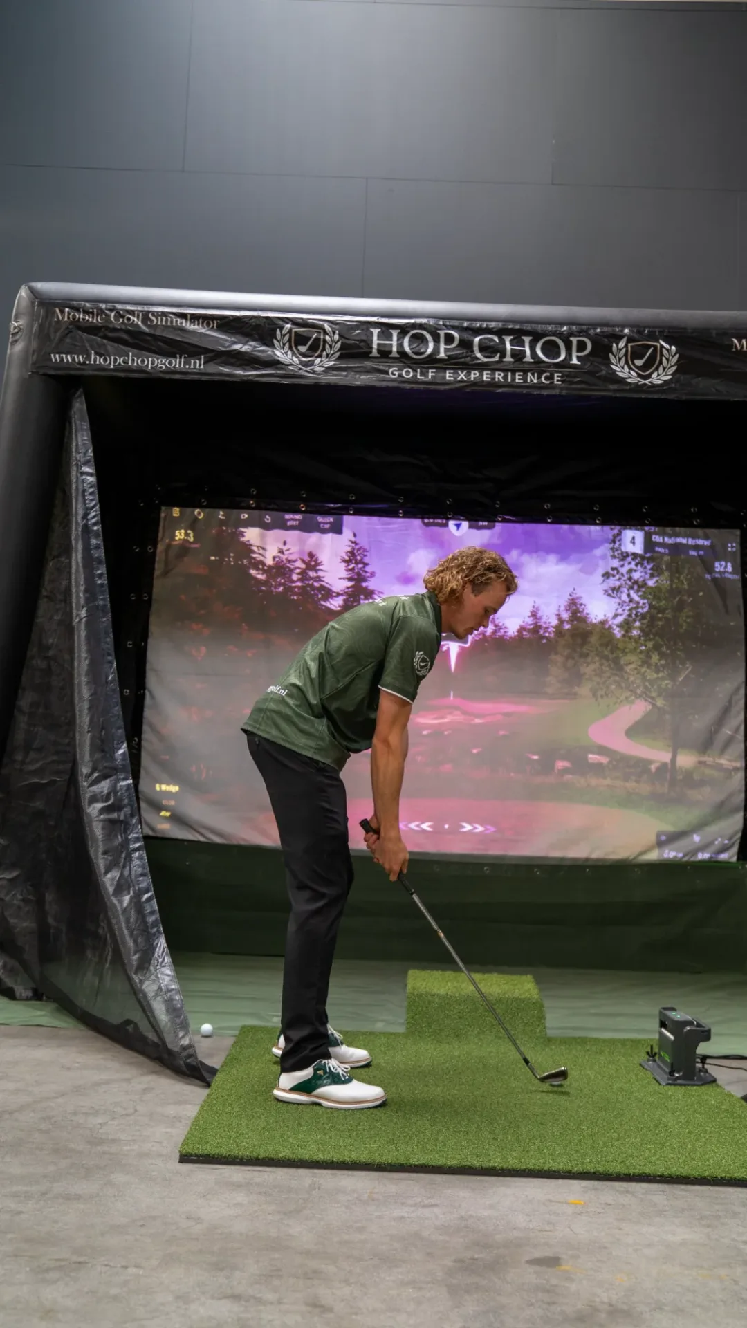 Golfer staat klaar voor de afslag op de mat van de mobiele golfsimulator van HOP CHOP