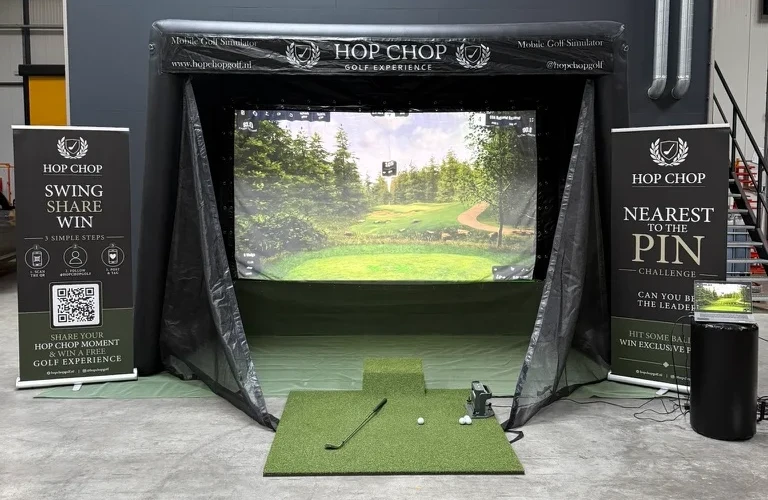 De mobiele golfsimulator van HOP CHOP met scherm, afslagmat en banners, klaar voor gebruik op locatie
